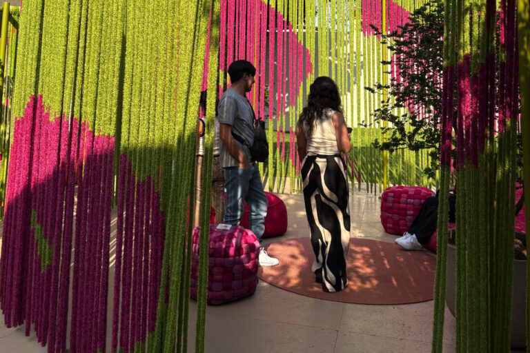 Ein grüner Sichtschutz mit pinken Beerenelementen auf der Mailand Design Week