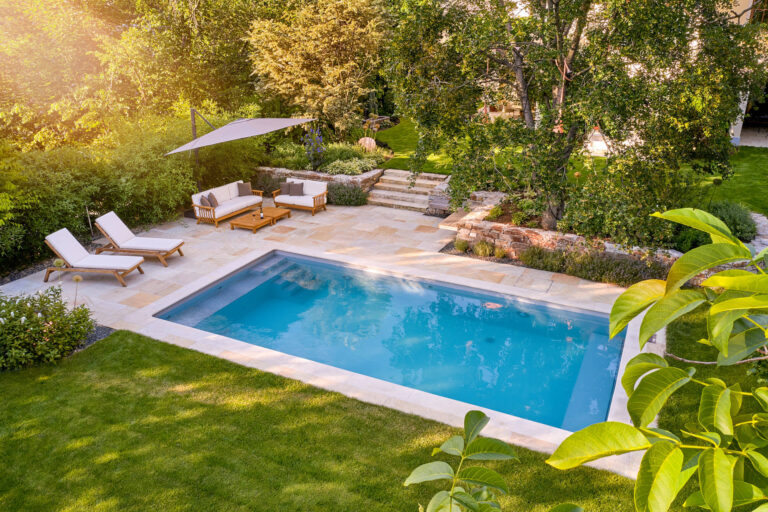 „Gartenanlage mit Pool, Natursteinterrasse, Sitz- und Liegebereich sowie üppiger Bepflanzung und altem Baumbestand.